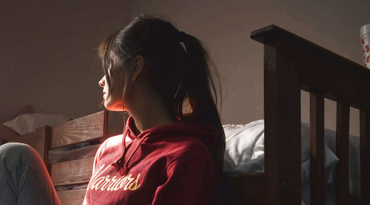 Sad woman sitting next to bed