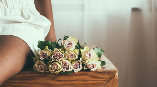 Woman sitting on table with bouquet of roses