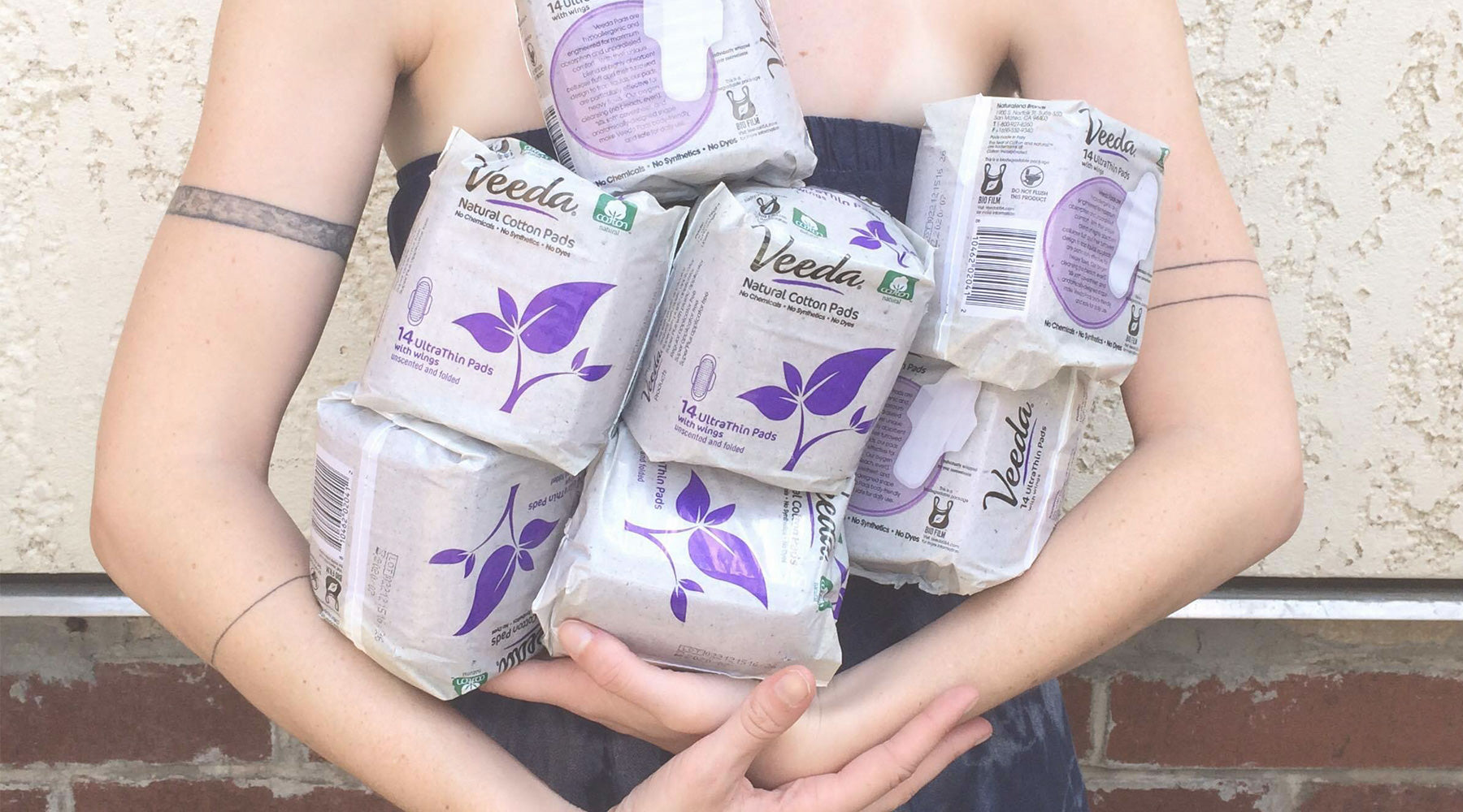 Woman holding an armful of Veeda feminine pads